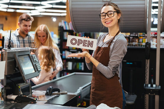 happy woman cashier holding open sign while in bankruptcy